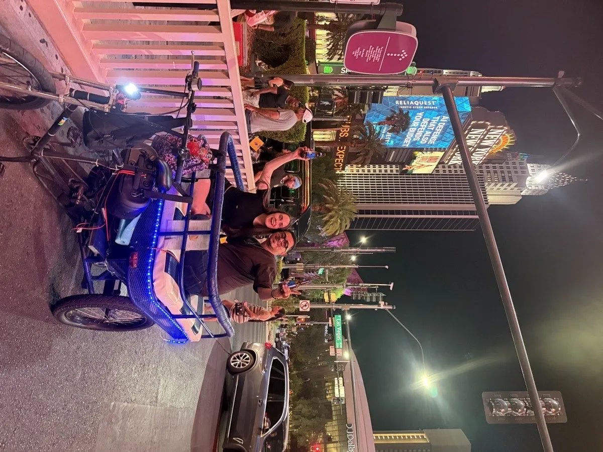 Vegas Bike Cab pedicab with riders in front of the New York-New York casino facade